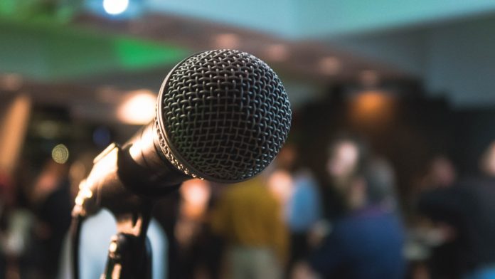 Speaker presenting confidently to a large audience in a modern conference hall
