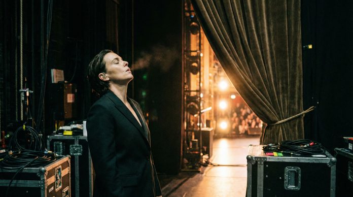 Presenter backstage taking a deep breath before going on stage with bright stage lights visible